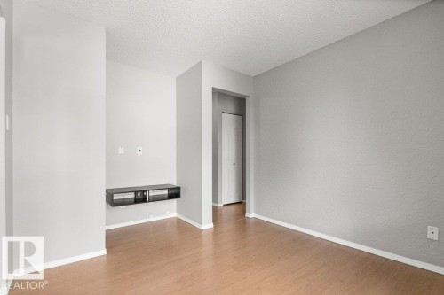 Wood-finish flooring with white baseboards, light gray wall paint, and a built-in media console - #4 14620 26 St Nw, Edmonton, AB 