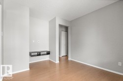 Wood-finish flooring with white baseboards, light gray wall paint, and a built-in media console - 