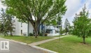 Two-story building with white siding, exterior stair access, and private balconies - #4 14620 26 St Nw, Edmonton, AB 