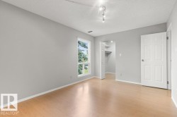 Wood-finish flooring, white trim, track lighting, a window, and an integrated closet with shelving - 