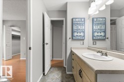 Vanity with integrated sink and chrome faucet, under-counter cabinetry, wall-mounted light fixture, and patterned floor tile - 