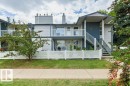 Multi-story exterior with light-colored siding, a white picket fence, and a concrete sidewalk - #4 14620 26 St Nw, Edmonton, AB 