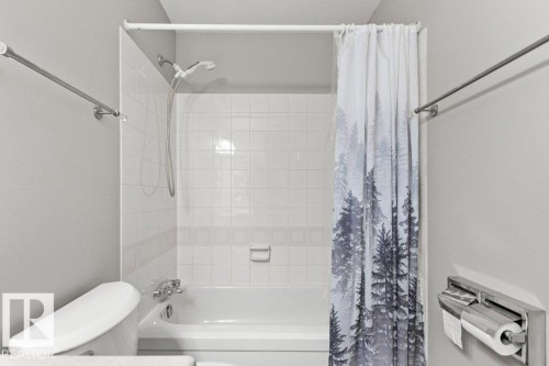 Bathtub with white tile surround, integrated shower, and wall-mounted shower head - #4 14620 26 St Nw, Edmonton, AB 