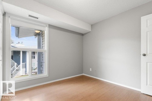 Bright interior with wood-finish flooring, white trim, and a white paneled door - #4 14620 26 St Nw, Edmonton, AB 
