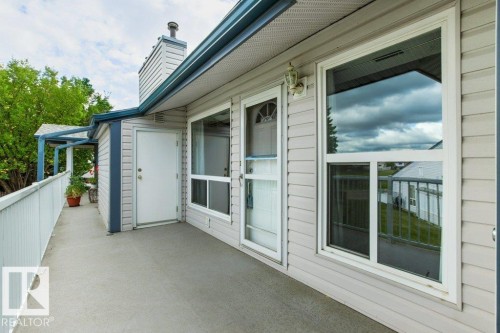Exterior siding with white trim, a screen door, and multiple windows - #4 14620 26 St Nw, Edmonton, AB 