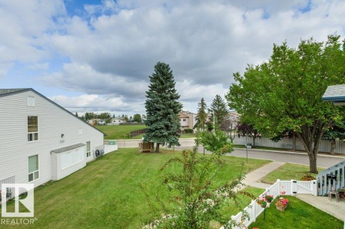 Expansive green space featuring mature trees and a manicured lawn - #4 14620 26 St Nw, Edmonton, AB 