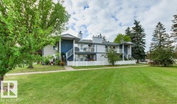 Multi-level exterior with balconies, featuring a white picket fence, mature trees, and a concrete walkway - 
