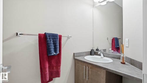 Wall-mounted mirror, vanity with an integrated sink, polished chrome faucet, and cabinet storage - 1709 64 Street Sw, Edmonton, AB 
