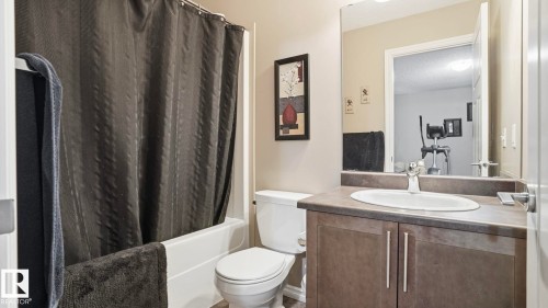 Tub and shower combination, single vanity with integrated sink, wall-mounted mirror, and wood-finish flooring - 1709 64 Street Sw, Edmonton, AB 