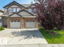 Duplex exterior featuring stone accents, light-toned siding, and dark trim - 1709 64 Street Sw, Edmonton, AB 