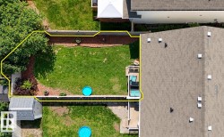 Expansive backyard featuring a manicured lawn, established landscaping, and a fenced perimeter - 