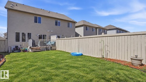 Expansive fenced backyard featuring a grassy lawn, wood privacy fence, and a multi-level wood deck - 1709 64 Street Sw, Edmonton, AB 