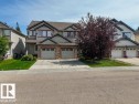 Duplex exterior with attached two-car garage, stone veneer accents, and a paved driveway - 1709 64 Street Sw, Edmonton, AB 