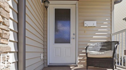 Stone veneer accent, horizontal siding, white entry door with frosted glass panel, recessed porch, and white railing - 1709 64 Street Sw, Edmonton, AB 