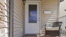 Stone veneer accent, horizontal siding, white entry door with frosted glass panel, recessed porch, and white railing - 1709 64 Street Sw, Edmonton, AB 