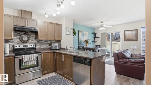 Kitchen featuring stainless steel appliances, wood-finish cabinetry, tile backsplash, and track lighting - 1709 64 Street Sw, Edmonton, AB 