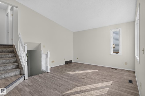 Vaulted ceiling, wood-finish flooring, white painted walls, white banister, and carpeted stairs - 3722 34A Avenue Nw, Edmonton, AB 