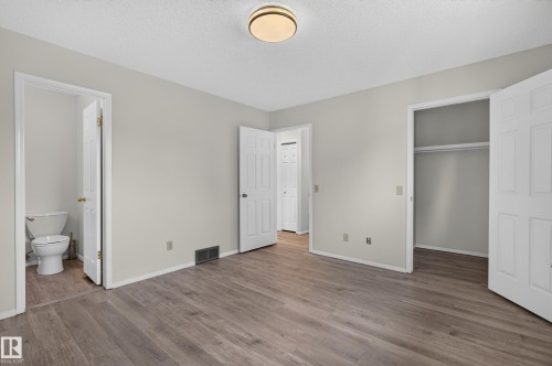 Wood-finish flooring, neutral wall tones, white trim, and a built-in closet with shelving - 3722 34A Avenue Nw, Edmonton, AB 