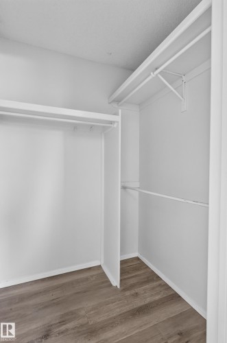 White walls with wood-finish flooring and multiple clothing rods - 3722 34A Avenue Nw, Edmonton, AB 