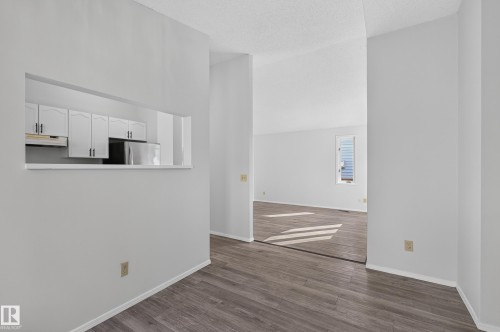 Pass-through window, white cabinetry, stainless steel appliance, wood-finish flooring, vaulted ceiling - 3722 34A Avenue Nw, Edmonton, AB 