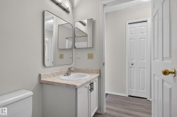Vanity with a single basin sink, wall-mounted mirror, and overhead lighting - 