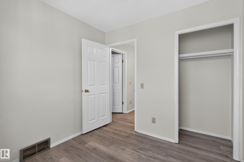 Neutral wall paint, wood-finish flooring, white trim, and a built-in closet with rod - 3722 34A Avenue Nw, Edmonton, AB 