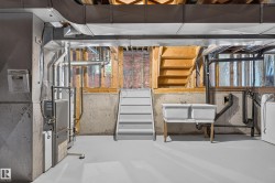 Finished basement space featuring concrete walls, exposed ceiling joists, and a utility sink - 