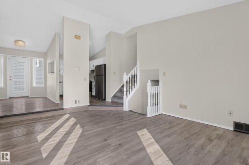 Wood-finish flooring, white walls, white staircase with balusters, and a decorative ceiling light fixture - 3722 34A Avenue Nw, Edmonton, AB 