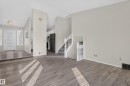 Wood-finish flooring, white walls, white staircase with balusters, and a decorative ceiling light fixture - 3722 34A Avenue Nw, Edmonton, AB 