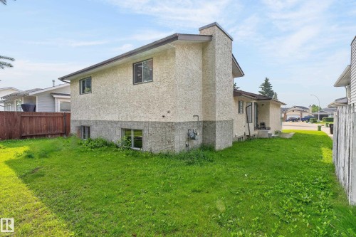 Stucco exterior with a prominent chimney, concrete block foundation, and multiple windows - 3722 34A Avenue Nw, Edmonton, AB 