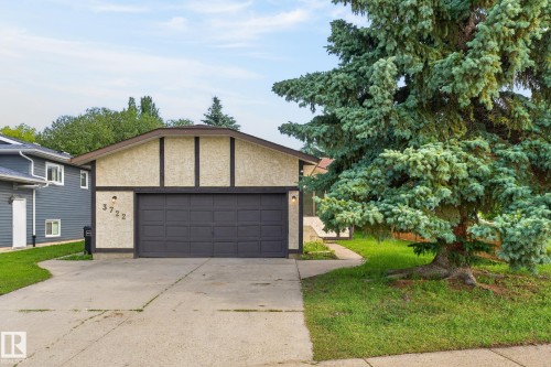 Front exterior featuring a stucco finish, dark trim accents, and a prominent garage door - 3722 34A Avenue Nw, Edmonton, AB 