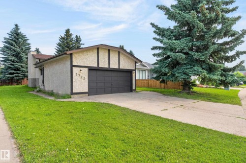 Stucco exterior with contrasting trim, attached garage with dark panel door, concrete driveway, and front lawn - 3722 34A Avenue Nw, Edmonton, AB 
