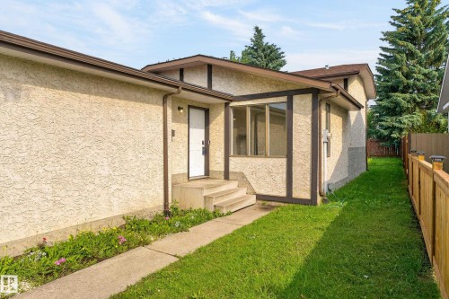 Stucco exterior with contrasting trim, concrete walkway, established lawn, and wood privacy fencing - 3722 34A Avenue Nw, Edmonton, AB 