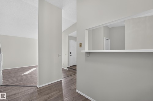 Wood-finish flooring throughout, light gray wall paint, and a pass-through window with a built-in ledge - 3722 34A Avenue Nw, Edmonton, AB 