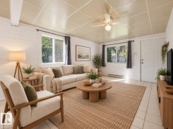 Wood-paneled walls, tile flooring, multiple windows, recessed ceiling, and a ceiling fan with integrated lighting - 