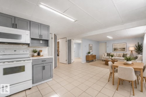 Kitchen featuring gray cabinetry with black hardware, subway tile backsplash, and white appliances - 11841 71 Street Nw, Edmonton, AB 