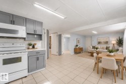Kitchen featuring gray cabinetry with black hardware, subway tile backsplash, and white appliances - 