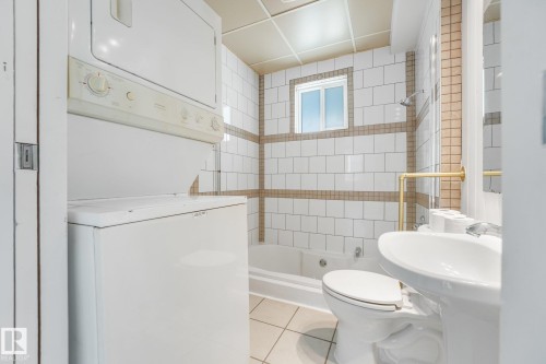 White subway tile surround with horizontal accent bands, white pedestal sink, white toilet, and a built-in bathtub with shower - 11841 71 Street Nw, Edmonton, AB 