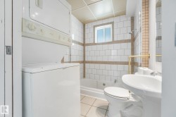 White subway tile surround with horizontal accent bands, white pedestal sink, white toilet, and a built-in bathtub with shower - 
