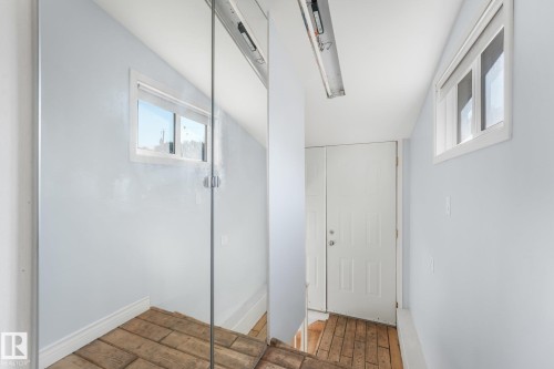 Wood-finish flooring, white paneled door, and multiple windows providing ambient light - 11841 71 Street Nw, Edmonton, AB 