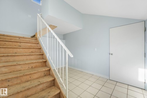 Wood staircase with a white metal railing, tile flooring, and a window - 11841 71 Street Nw, Edmonton, AB 
