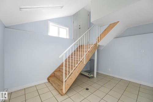 Tiled flooring with light-toned walls, open wooden staircase with white railings, and a window providing natural light - 11841 71 Street Nw, Edmonton, AB 