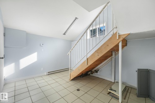 Tiled flooring, white painted walls, and wood staircase with white railing - 11841 71 Street Nw, Edmonton, AB 
