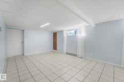 Expansive room featuring light-toned tile flooring, light-colored walls, and a suspended ceiling - 