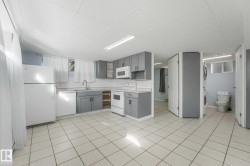 Tile flooring, gray cabinetry, white appliances, integrated sink, and a stacked washer and dryer - 