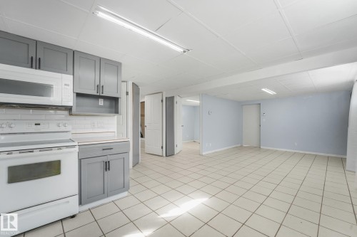 White tile flooring, gray cabinetry, white subway tile backsplash, white built-in microwave, and white electric range - 11841 71 Street Nw, Edmonton, AB 