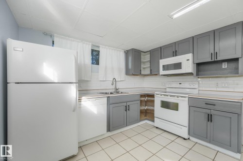 Kitchen featuring gray cabinetry, white appliances, tile flooring, subway tile backsplash, and a stainless steel sink - 11841 71 Street Nw, Edmonton, AB 