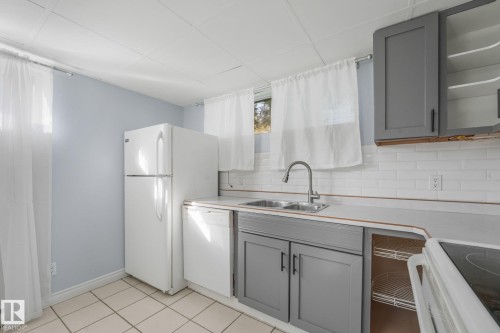 Tile flooring, white subway tile backsplash, dual basin stainless steel sink, light gray lower cabinetry, and light gray upper cabinetry - 11841 71 Street Nw, Edmonton, AB 