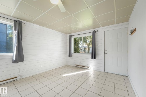 White paneled walls, white tiled flooring, white ceiling fan, and white paneled entry door - 11841 71 Street Nw, Edmonton, AB 