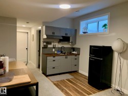 Compact kitchen featuring gray cabinetry, wood-finish countertops, stainless steel sink, and a black refrigerator - 